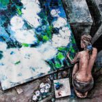Painting Desires of Life – Motivational abstract canvas artwork featuring a female artist working on a vibrant blue, green, and white palette knife painting.